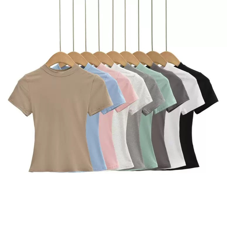 Row of plain t-shirts in various colors on hangers against a white background